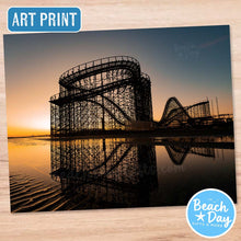 Load image into Gallery viewer, Wildwood's Great White Roller coaster silhouette at sunset with reflection on water